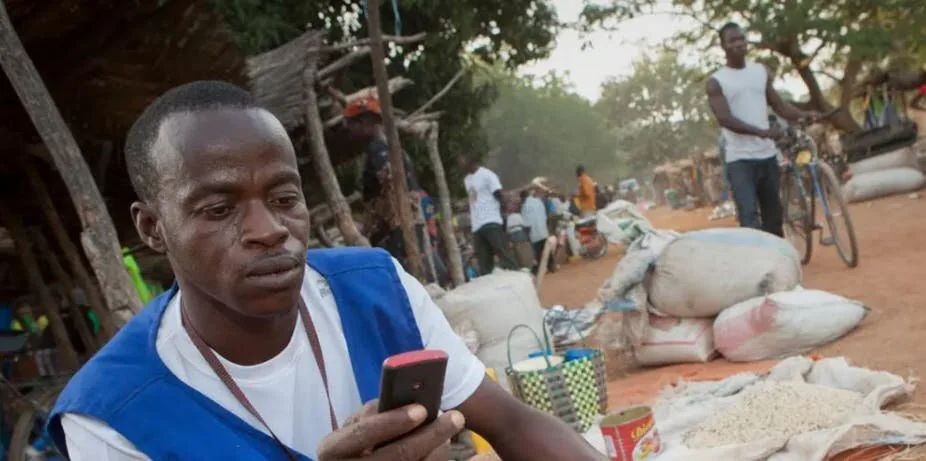 Farmer using a phone at a rural market.